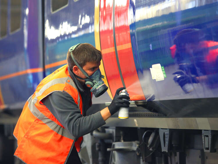 Man in PPE sprays train for installation for Aura Brand Solution