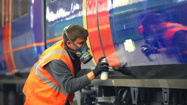 Man in PPE sprays train for installation for Aura Brand Solution
