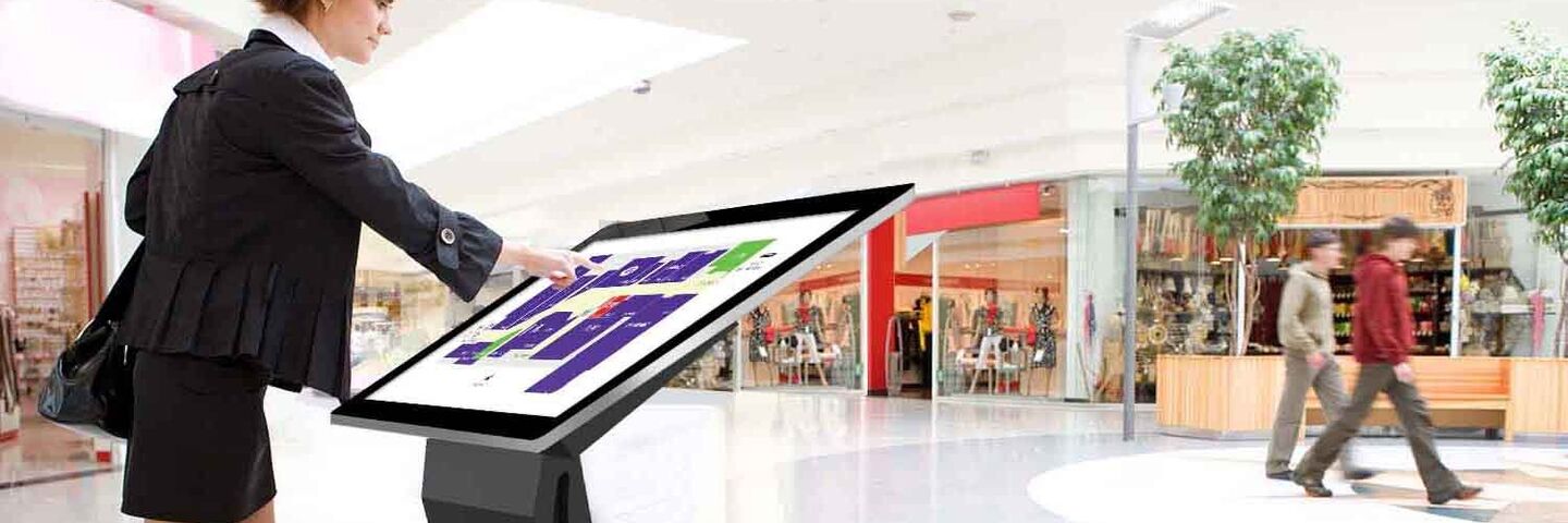 woman using digital signage touchscreen kiosk in retail location