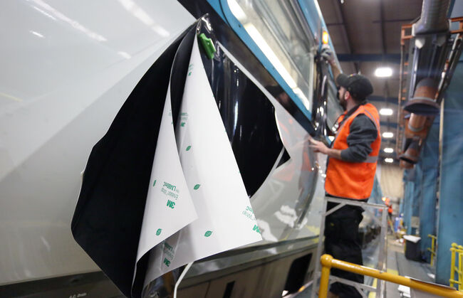 Fitter applies EcoFilm 3M 480 graphics to TfW train