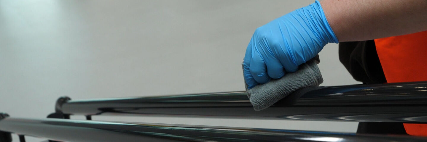 Man wipes antibacterial & antiviral Virus Guard Shield Protect onto a handrail for 3 year protection against germs