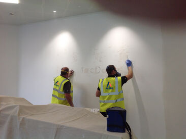 Team carrying out surface repairs, preparation and paint for new signage to wall