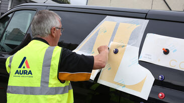 Man applying branded graphics onto Addison Lee vehicle